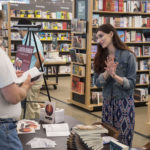 L. Austen Johnson stands gesturing while at an event at barnes and noble